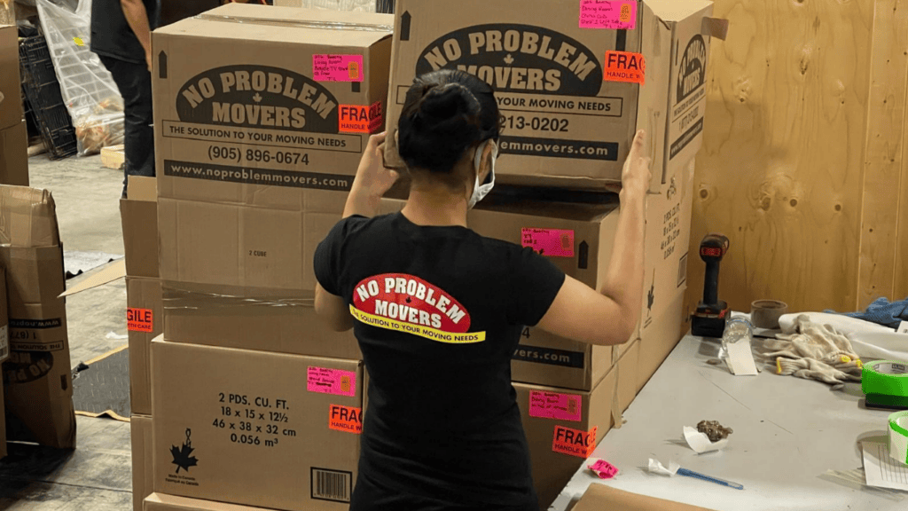 No Problem Movers team member packing and labelling moving boxes in a warehouse, preparing household belongings for a safe and organized move.